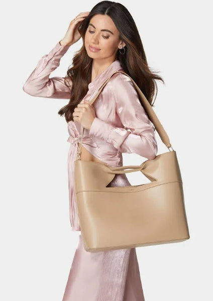 Woman holding a beige handbag against a white background