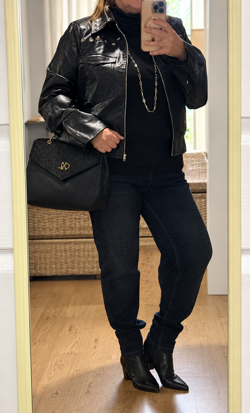 Caroline wearing the Andrée by Unit black studded vegan-leather moto jacket with a black handbag